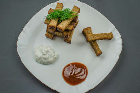 Toasts are fried on a frying pan with spices. Served on a white plate with garlic sauceの写真素材