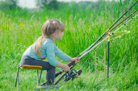 little girl fishing on river near forestの写真素材