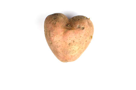 Ugly potato in the heart shape on a gray background. Unnormal vegetable or food.の写真素材