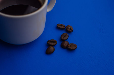 Cup of Coffee espresso with offee beans on blue background. Flat lay, creative design. Morning black...