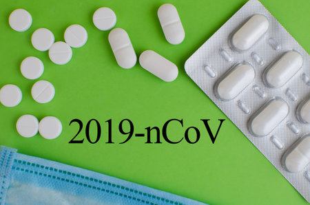Text phrase Coronavirus on a green background with medicines and protective masks. Novel coronavirus...