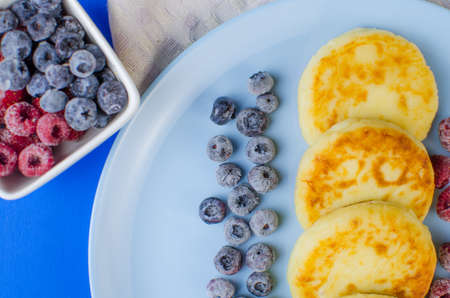 Cheesecakes in a blue dish with frozen fruit. Homemade, delicious food. Copy space for textの写真素材
