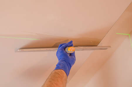 The Builder puts plaster on the wall.Hand holding a spatula with construction mix and smoothes out bumps.Repair the wall.Plaster the wall with a putty knife.の写真素材