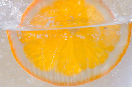 An orange falling into the water. Bright background. Close upの写真素材
