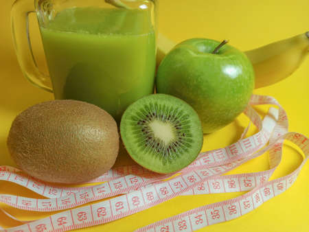 Green healthy smoothie in glass jar: banana, kiwi, green apple. Healthy drink on yellow background. Copy space for textの写真素材