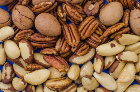 Pekan and brazil nuts on blue background. Healthy foodの写真素材