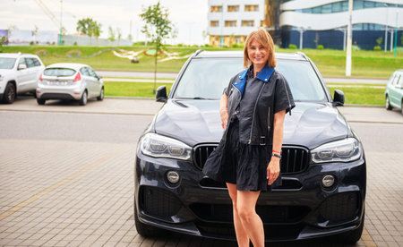 Attractive girl dressed in a leather jacket standing by the car.