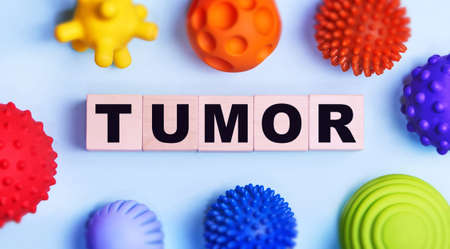 Tumor - text on wooden cubes against the background of a toy virus. Medicine concept.の写真素材