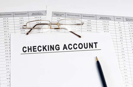 Checking account inscription on a sheet of paper against the background of glasses, pens and calculations.の写真素材