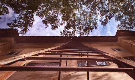 An iron staircase on the wall of the house leads to the roof of the building.の写真素材