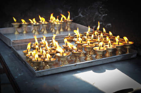 Butter lamps with flames near Bodhnath stupa in Kathmandu valley, Nepalの写真素材