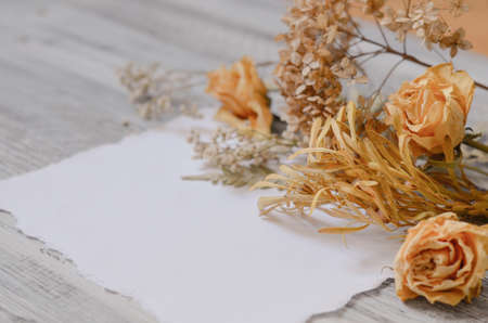 Vintage floral background with fern leaves, dried roses flowers, hydrangea and branches on rustic white wooden background. Border background vintage mock upの写真素材