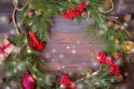 Christmas and New Year Decoration with Wreath of Pine Branches and Rowan, Orange Slices, Gift Box, Fir Cones on a Rustic Wooden Table, Copyspace backgroundの写真素材