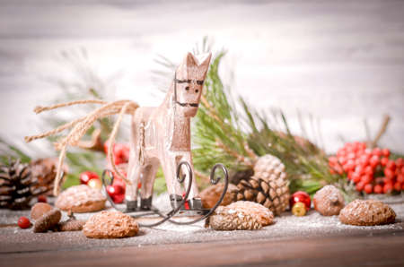 Christmas and New Year Decoration with Vintage Wooden Horse, Pine Branches, Oatmeal Cookies, Rowan, Walnuts, Fir Cones, on a Rustic Wooden Tableの写真素材