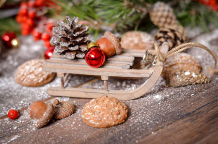 Christmas and New Year Decoration with Vintage Wooden Sled, Pine Branches, Oatmeal Cookies, Rowan, Walnuts, Fir Cones, on a Rustic Wooden Tableの写真素材
