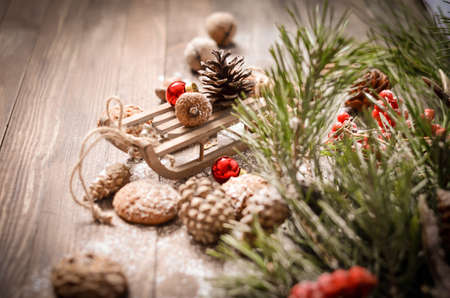 Christmas and New Year Decoration with Vintage Wooden Sled, Pine Branches, Oatmeal Cookies, Rowan, Walnuts, Fir Cones, on a Rustic Wooden Tableの写真素材