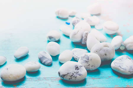 Close-up white textured pebbles lying in mess on blue table.の写真素材