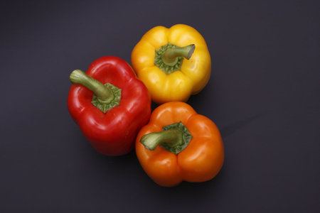 three peppers over dark grey background