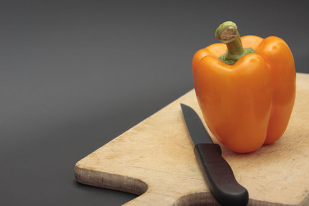 pepper on wood chopping board  over dark grey background
