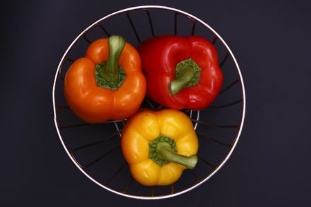 three peppers in chrome basket over dark grey backgroundの写真素材