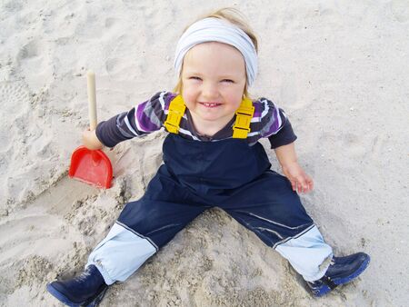 little girl with scoop playing in the sandの写真素材