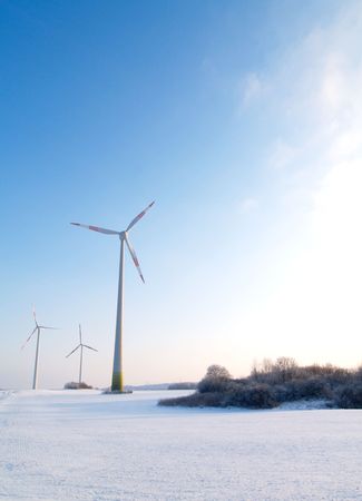 rural german winter landscape with wind turbines and sunny blue skyの写真素材