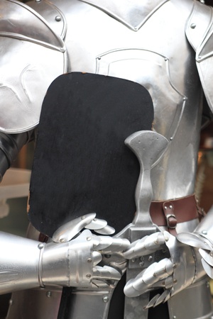 detail of an old knights plate armour holding a black board for your offersの写真素材