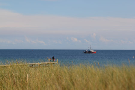 selective focus photo of a pier with trawler in the background, focus on trawler