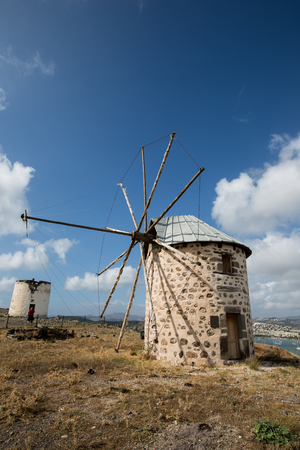old windmill with white clouds and blue skyの写真素材