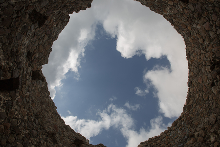 the roof of the old windmill ruins with white clouds and blue skyの写真素材
