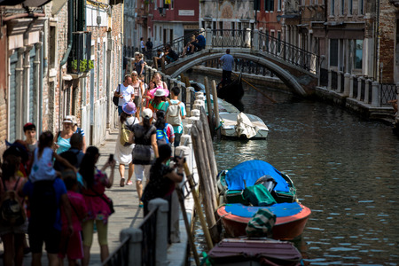 Venice city scape with narrow streets, bridges,buildings and boats on canal in beautiful romantic city  Venice Italy  Tourists walk along the Street at sunny summer dayの写真素材