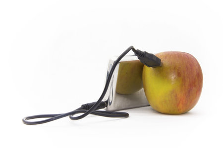 An apple connected to an MP3 player over a wire cable.の写真素材