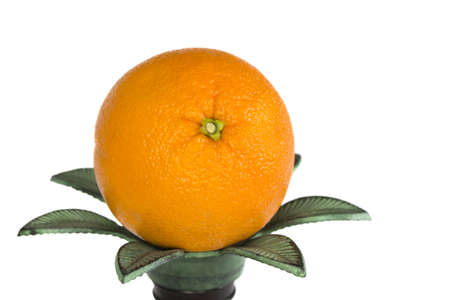 A single ripe orange sittng on a candle holder a white backgroundの写真素材