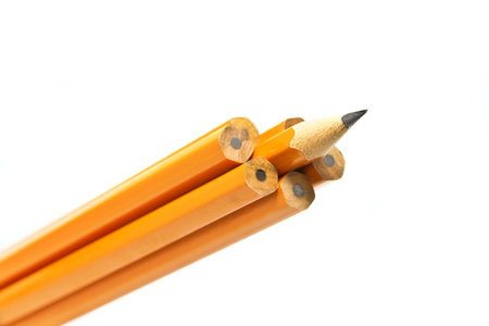 a sharp pencil sticking out form a croud of dull pencilsの写真素材