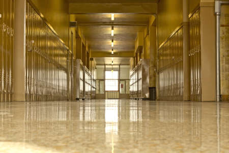 An empty high school corridor with a bright light at the end of the hallwayの写真素材