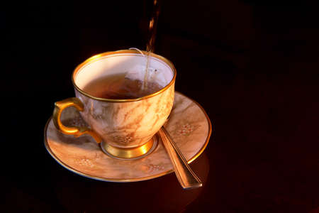 Boiling hot water being poured into a cup on a saucer with a tea bagの写真素材