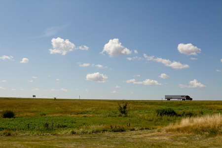 A big 18 wheeler truck traveling on a highway which appears to be invisibleの写真素材