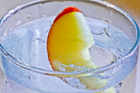The motion of a slice of apple splashing into a glass of waterの写真素材