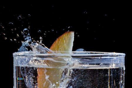 The motion of a slice of apple splashing into a glass of waterの写真素材