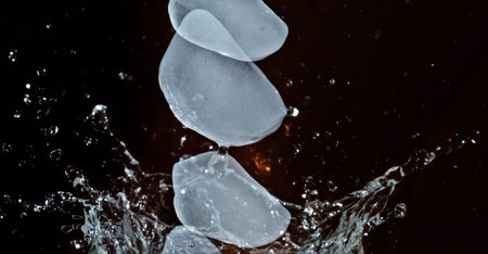 The motion of ice splashing into a glass of water frozen in timeの写真素材