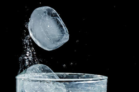 The motion of ice splashing into a glass of water frozen in timeの写真素材