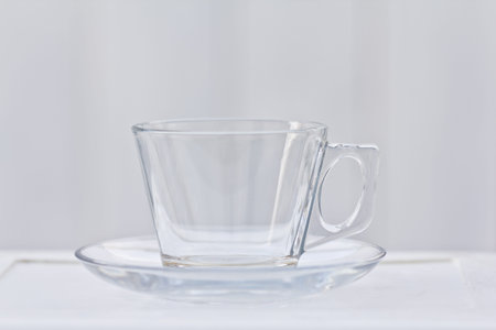 A clear glass coffee cup with a saucer that is empty.の写真素材