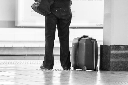 A person with a suitcase patiently waiting for a train at a the train stationの写真素材