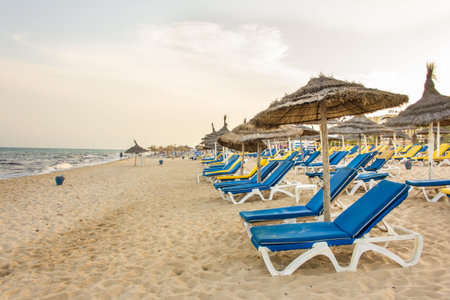Hammamet beach with shades made of straw, blue beach chairs and beautiful white sand along the coast of the Mediterranean seaのeditorial素材