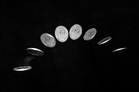 Stroboscopic effect created using flash capturing the motion of a coin as it is being tossed in the...