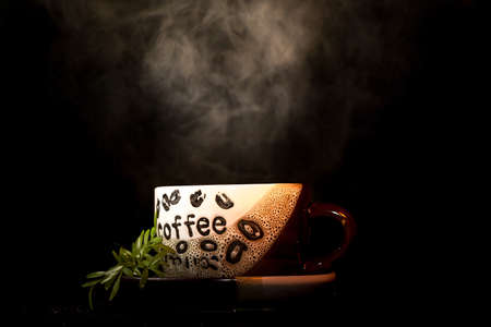 A low key image of a hot cup of coffee with steam blowing upの写真素材