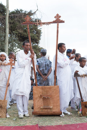 Clergyman stands next to a big Begena, a traditional Ethiopian string instrument with ten strings...