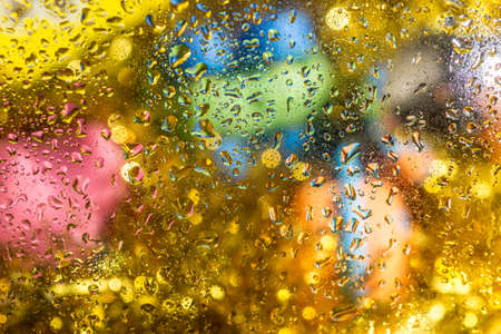 A bright colorful background image of water droplets on a glass surfaceの写真素材