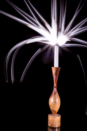 A candle in a holder glowing with bright streaks of painted lightの写真素材