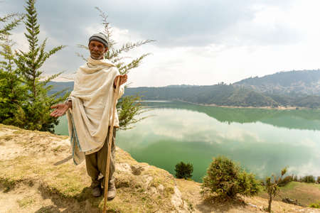 Wonchi, Ethiopia - February, 2014: An elderly resident of a village which promotes eco-tourism to improve the livelihood of the local community, greets tourists who come to visit the magnificent Wonchi Crater Lake, on 9 February, 2014, Wonchi, Ethiopiaのeditorial素材